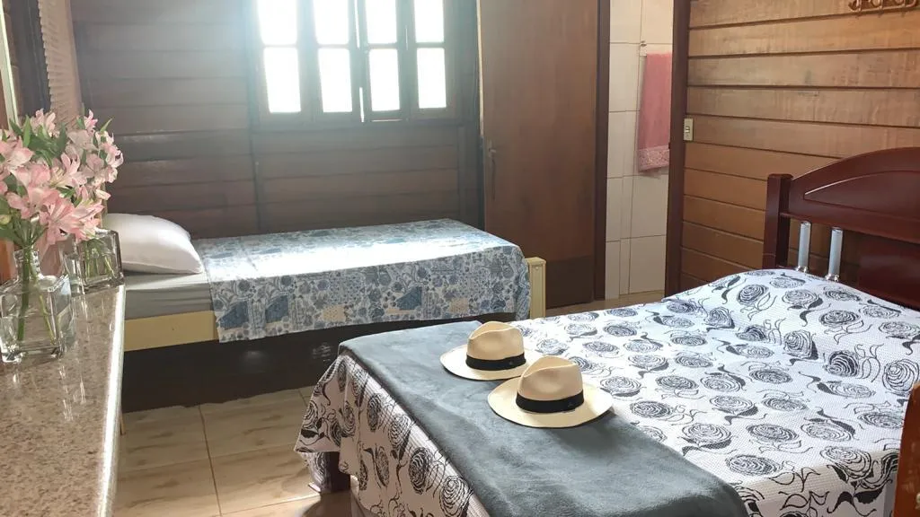 Suíte do Rancho SPPA com cama de casal, cama de solteiro e janela de madeira